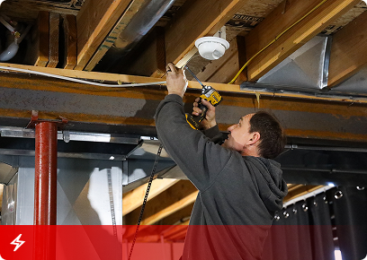 KB Complete technician installing a light fixture between basement floor joists