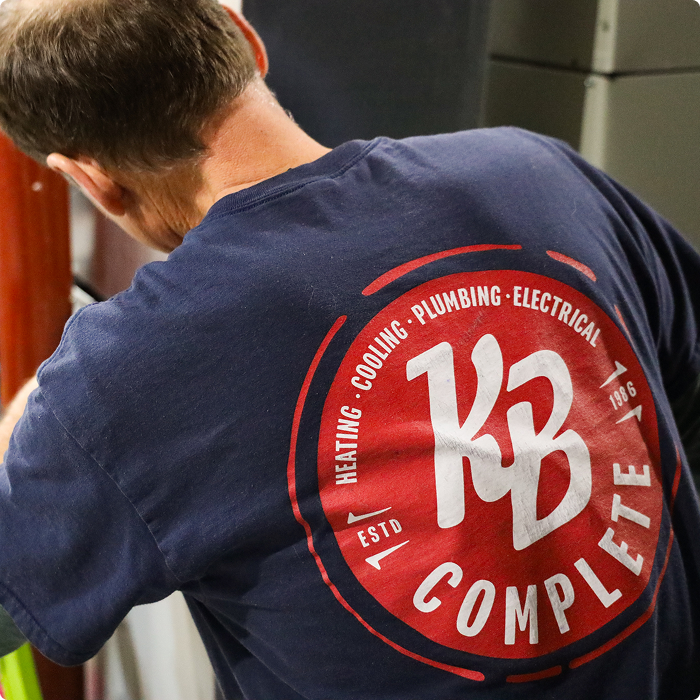 KB Complete technician seen from behind, wearing a shirt with the heating, cooling, plumbing and electrical logo